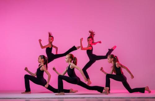 ballet girls with long loose hair in black tight-fitting suits dancing on a red background
